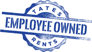 Distressed blue stamp graphic with the words "EMPLOYEE OWNED" prominently displayed horizontally across the center. Above it, arced text reads "TATES", and below it, also arced, is "RENTS". The stamp has an irregular, jagged circular border and two horizontal bars extending from the central text.